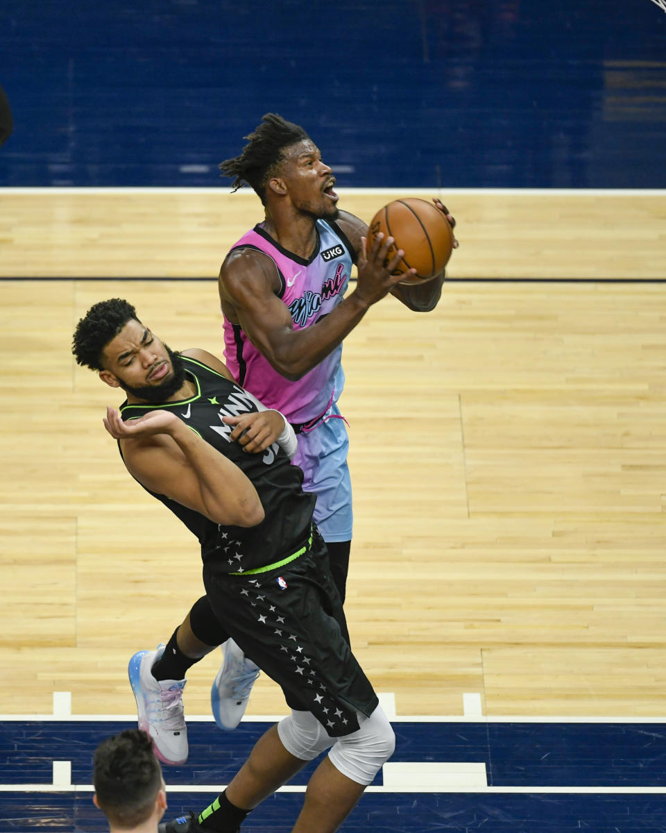 Minnesota Timberwolves center Karl-Anthony Towns, left, fouls Miami Heat forward Jimmy Butler as he goes up for a shot during the first half of an NBA basketball game Friday, April 16, 2021, in Minneapolis. (AP Photo/Craig Lassig)