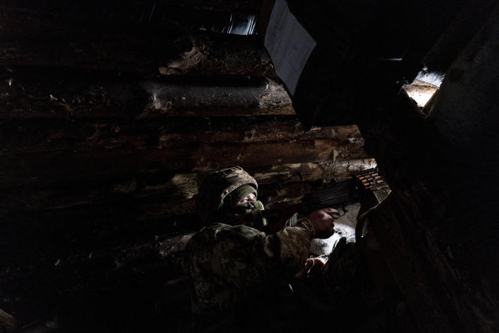 A Ukrainian serviceman keeps ready a machine gun in his shelter near the front-line town of Krasnohorivka, eastern Ukraine, Friday, March 5, 2021. The country designated 14,000 doses of its first vaccine shipment for the military, especially those fighting Russia-backed separatists in the east. But only 1,030 troops have been vaccinated thus far. In the front-line town of Krasnohorivka, soldiers widely refuse to vaccinate. (AP Photo/Evgeniy Maloletka)