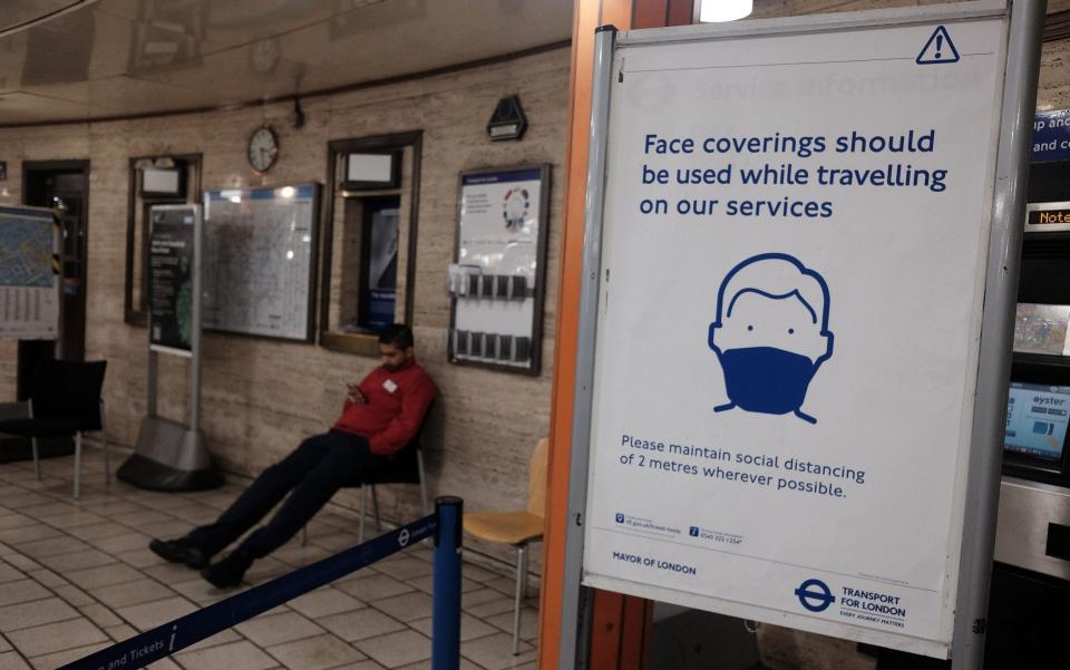 A sign advising the use of face coverings for commuters at Piccadilly Circus Underground station in London - PA