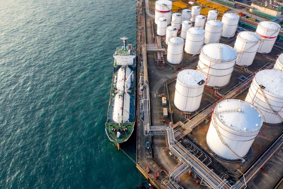 A ship docked next to liquid fuels storage tanks.