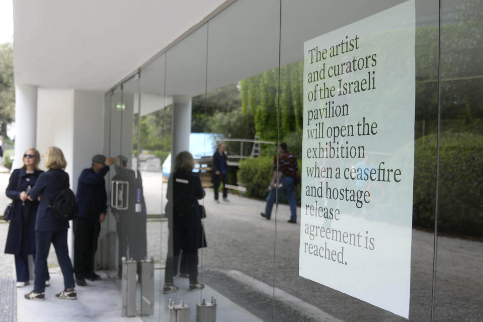 People stand in front of the closed Israeli national pavilion at the Biennale contemporary art fair in Venice, Italy, Tuesday, April 16, 2024 The sign at right announced that the artist and curators representing Israel at this year's Venice Biennale won't open the Israeli pavilion until there is a cease-fire in Gaza and an agreement to release hostages taken Oct. 7.(AP Photo/Luca Bruno)