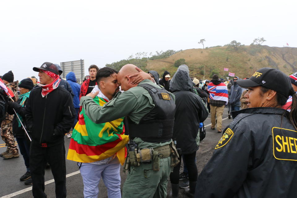 In this Monday, July 22, 2019, photo provided by the State of Hawaii, Mauna Kea law enforcement personnel interact with protesters blocking a road to the summit of Mauna Kea, a site considered sacred in Hawaii. Scientists want to build a telescope atop Mauna Kea because it is one of the best sites in the world for viewing the skies. The observatory would join 13 other telescopes already at the summit, though five are due to be decommissioned in a concession to telescope opponents. The Hawaii Supreme Court upheld the permit in 2018. (Dan Dennison/State of Hawaii via AP)