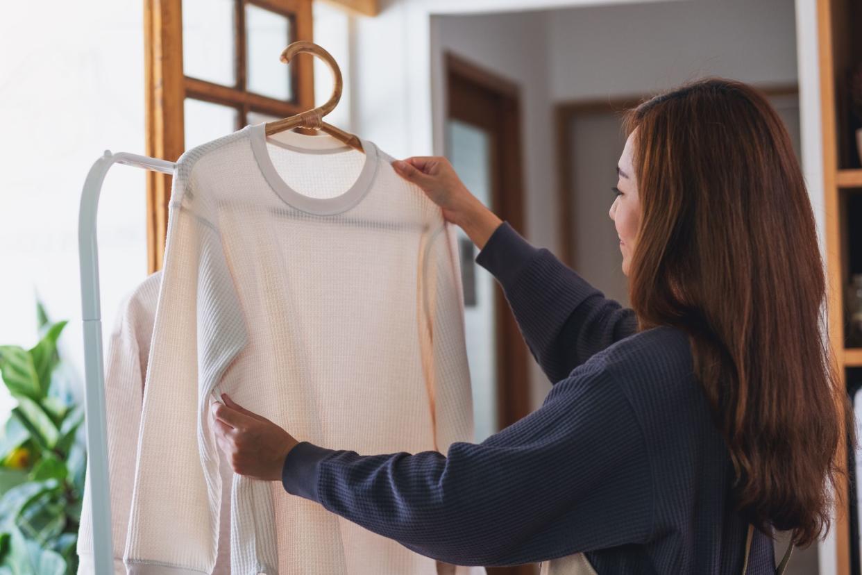 A housewife doing laundry, washing and hanging shirts on clothesline at home