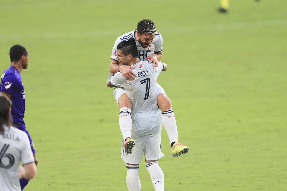 New England Revolution midfielder Kelyn Rowe (11) celebrates with forward Gustavo Bou (7) after an MLS playoff soccer match against Orlando City, Sunday, Nov. 29, 2020, in Orlando, Fla. (AP Photo/Matt Stamey)