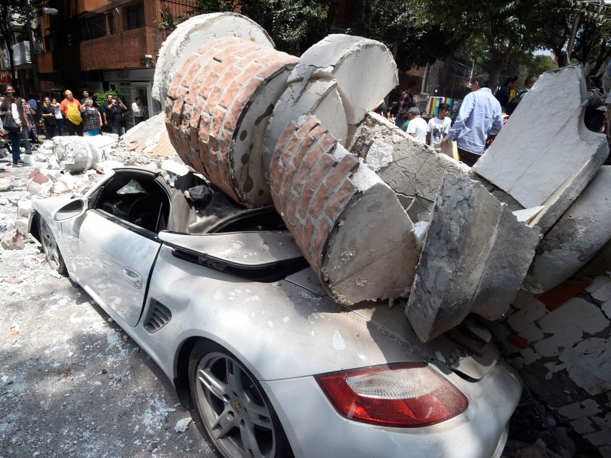 A car crashed by debris from a damaged building after a quake rattled Mexico City: AFP/Getty