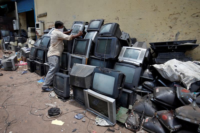 Un vendedor de chatarra acumula televisores desechados antes de desmantelarlos en un depósito en Ahmedabad, India, 2 de julio de 2020.