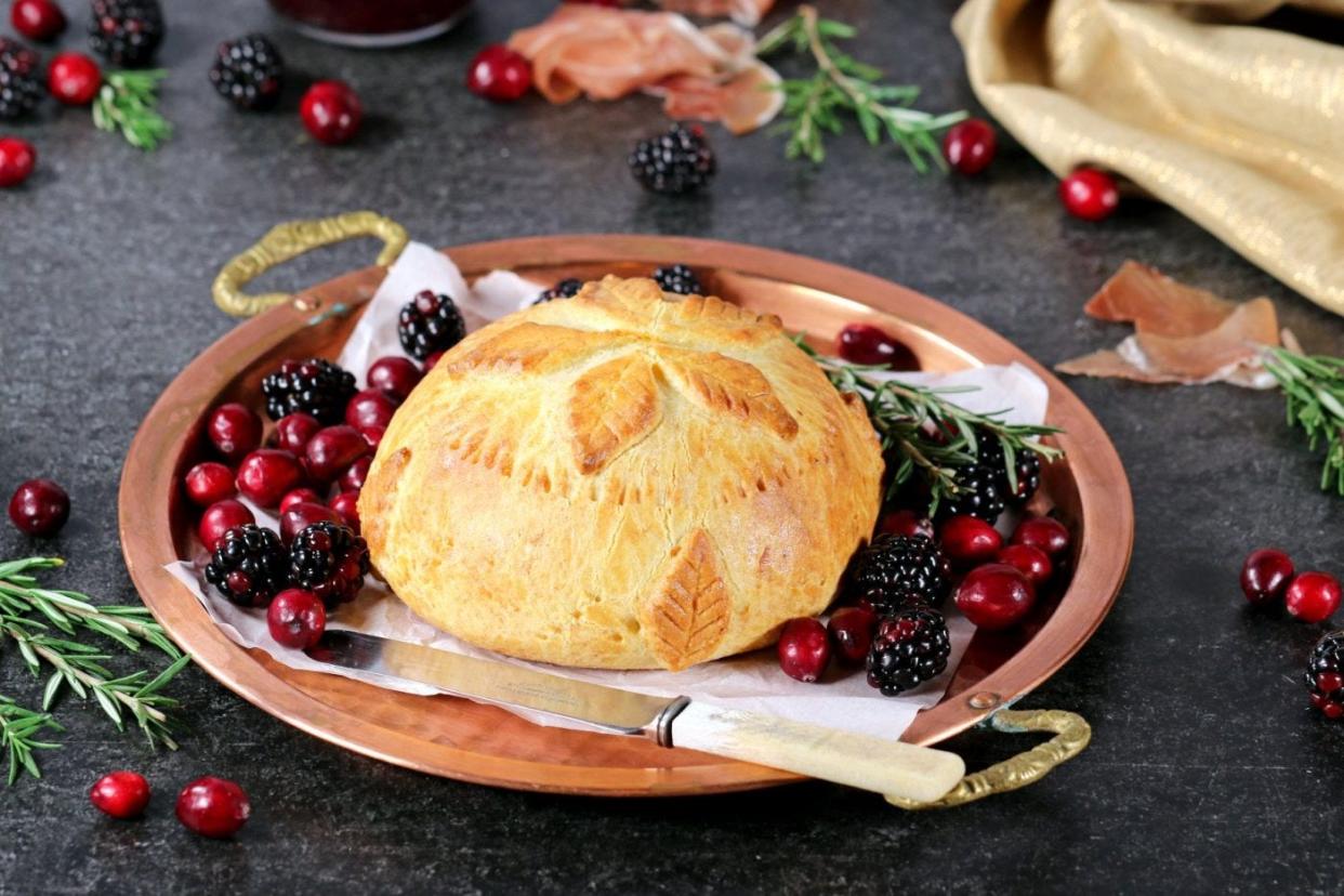 A wheel of prosciutto-wrapped Brie sits atop a layer of sweet, tangy, sugar-free cranberry sauce, all inside a blanket of delicious buttery, flaky, low-carb pastry.