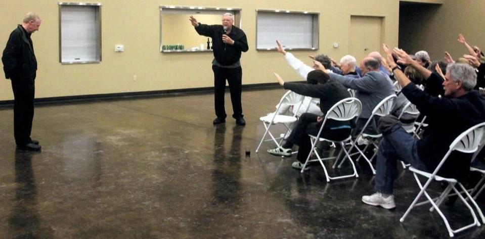 Parishioners stretch their hands out in prayer for Michael Kelly in 2012 at St. Joachim Catholic Church in Lockeford, hours after he was found liable in a Calaveras County civil trial of of assault, sexual assault and abuse. Kelly had served as priest at the church since 2004.