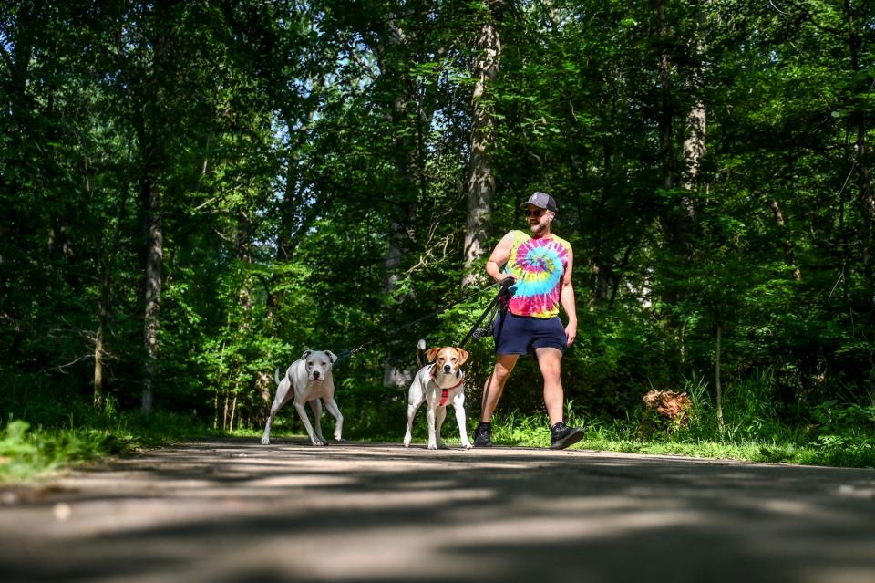 Patrick Cooper walks his dogs Peach, left, and Flaca at Scott Woods Park on Friday, June 30, 2023, in Lansing.