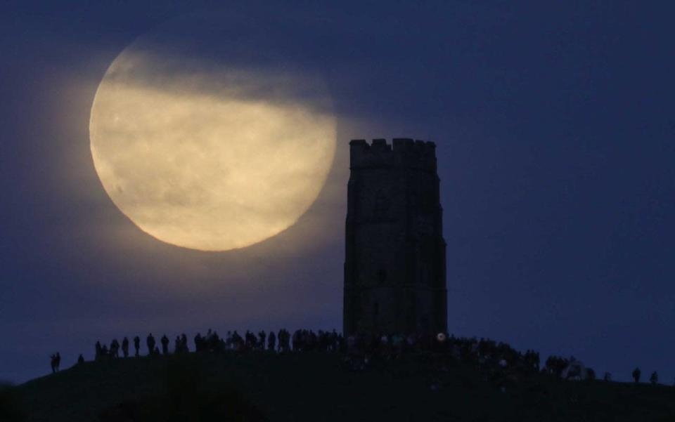 A full moon rises behind Glastonbury Tor as people gather to celebrate the summer solstice on June 20, 2016 in Somerset, England. (Photo by Matt Cardy/Getty Images)