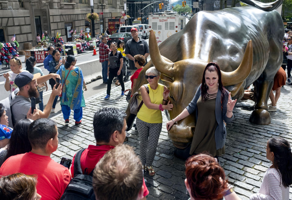 People gather around the popular lower Manhattan sculpture "Charging Bull," with a damaged right horn, Sunday, Sept. 12, 2019, in New York. A man was arrested Saturday afternoon for damaging the iconic Wall Street Charging Bull statue with an object resembling a banjo, local media reported. (AP Photo/Craig Ruttle)