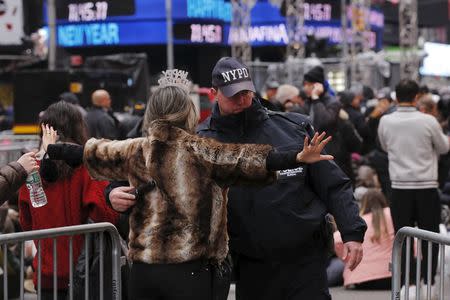 A woman is searched by a New York Police Department officer as she enters a pen to wait for the beginning of New Year's Eve festivities in the Times Square area of New York December 31, 2015. REUTERS/Lucas Jackson