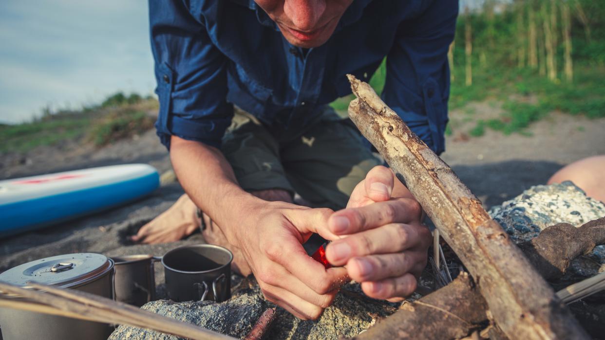  Man Lighting A Campfire On The Beach 