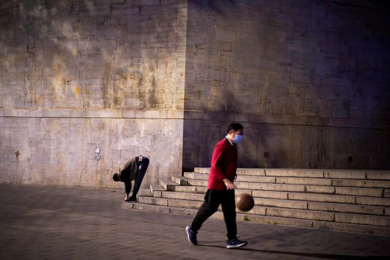 People wearing face masks exercise on a street in Wuhan