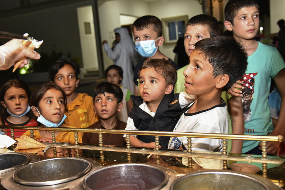 Afghan children who were evacuated from Afghanistan are served ice cream cones in a temporary housing compound, in Doha, Qatar, Aug. 22, 2021. Qatar played an out-sized role in U.S. efforts to evacuate tens of thousands of people from Afghanistan. Now the tiny Gulf Arab state is being asked to help shape what is next for Afghanistan because of its ties with both Washington and the Taliban insurgents now in charge in Kabul. (Qatar Government Communications Office via AP)