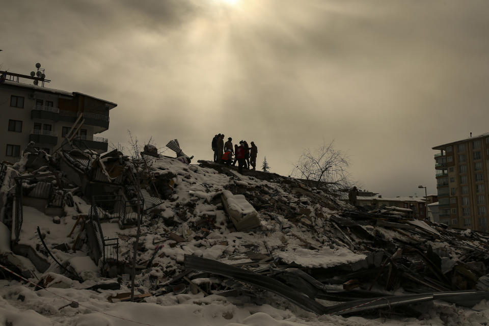 Un grupo de personas trata de llegar hasta otras atrapadas bajo los restos de un edificio derrumbado, en Malatya, Turquía, el 7 de febrero de 2023. (AP Foto/Emrah Gurel)