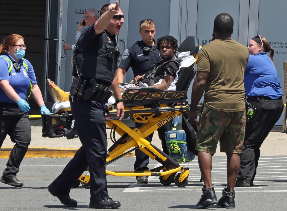 An officer tries to clean the scene as a victim is taken by paramedics to a waiting ambulance after a shooting at the Eastridge Mall Friday afternoon, June 10, 2022.