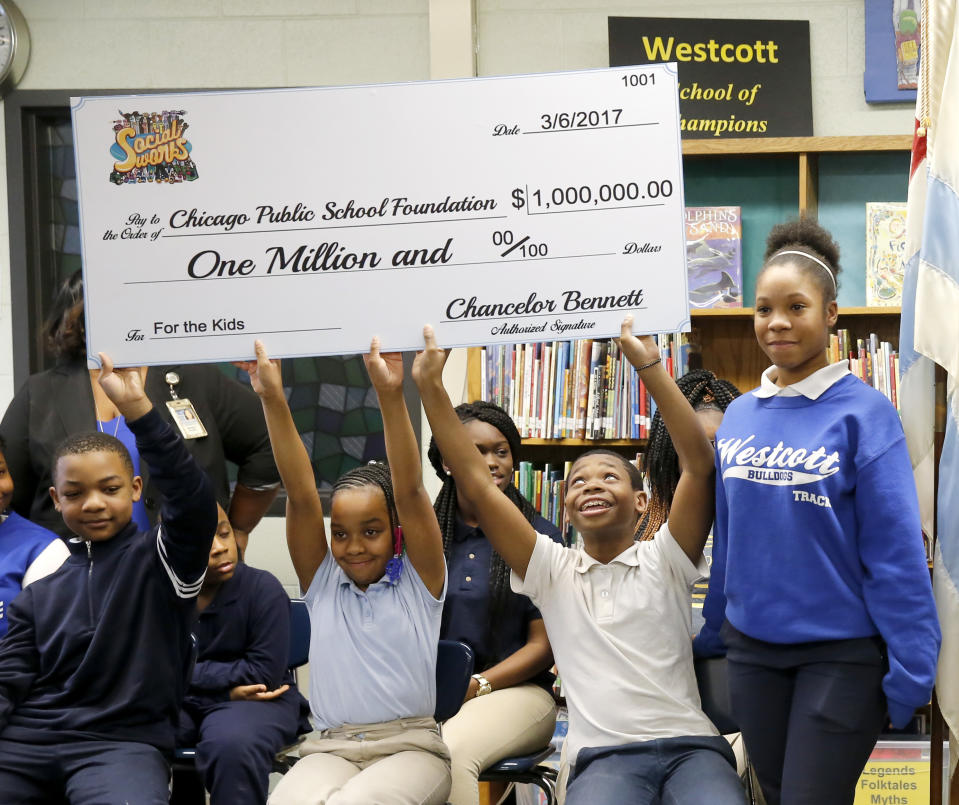 Students at the Westcott Elementary School on Chicago's South Side holds up a check, a gift of $1 million to the Chicago Public School Foundation, from Chance The Rapper during a news conference at the school Monday, March 6, 2017, in Chicago. The Grammy-winning artist is calling on Illinois Gov. Bruce Rauner to use executive powers to better fund Chicago Public Schools. (AP Photo/Charles Rex Arbogast)