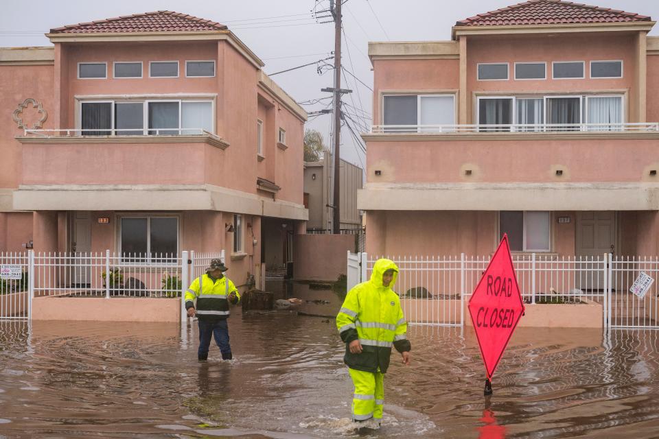 A cleaning crew walks through floodwaters in the Rio Del Mar neighborhood of Aptos, Calif., Monday, Jan. 9, 2023 (AP)