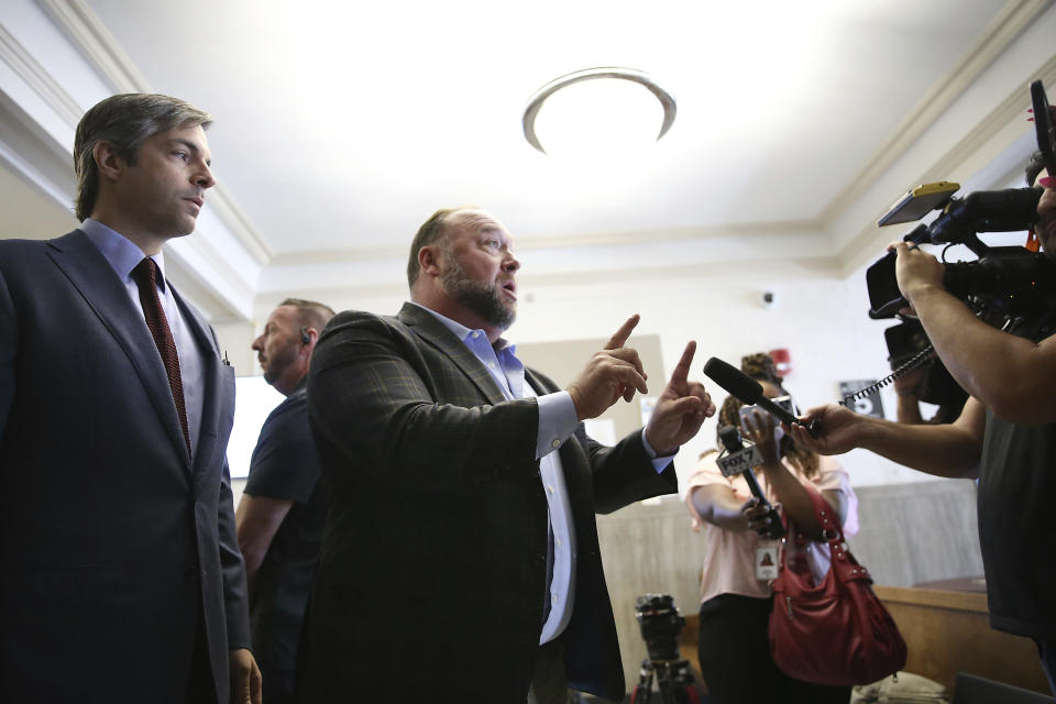 FILE - Alex Jones talks to media as his attorney, Andino Reynal, left, looks on during a midday break for the trial at the Travis County Courthouse in Austin, Texas, Tuesday, July 26, 2022. A Connecticut judge on Tuesday, Jan. 17, 022, ruled that Reynal committed misconduct but will not be disciplined, in connection with the improper disclosure of confidential medical records of relatives of Sandy Hook school shooting victims. (Briana Sanchez/Austin American-Statesman via AP, Pool, File)