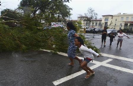 Residents rush to safety past a fallen tree during strong winds brought by Typhoon Haiyan that hit Cebu city, central Philippines November 8, 2013. REUTERS/Zander Casas