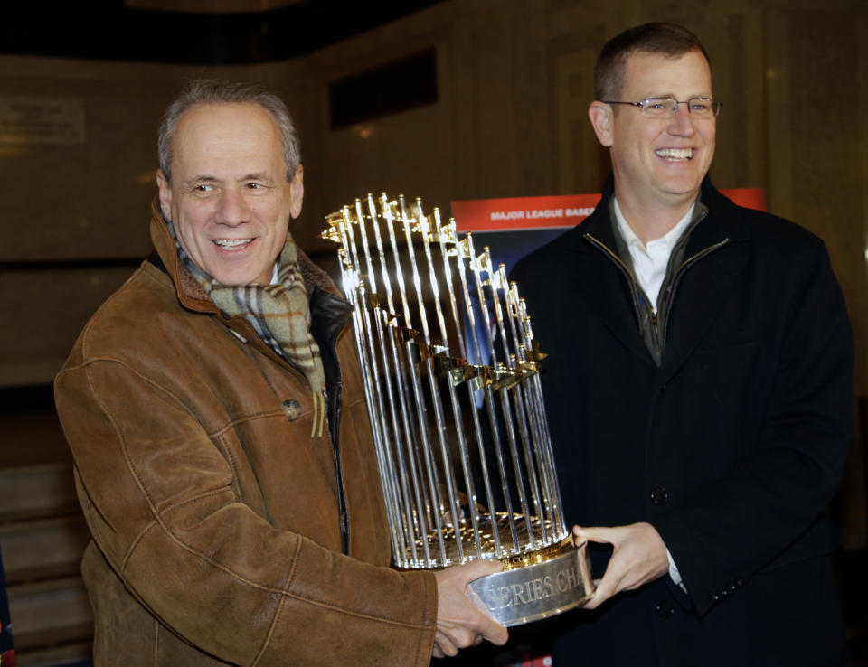 FILE -FILE - Boston Red Sox CEO Larry Lucchino, left, and Chief Operating Officer Sam Kennedy hold the 2013 World Series baseball trophy on the red carpet at the Wang Theatre before a screening of a DVD about the series in Boston., Nov. 23, 2013. Larry Lucchino, the force behind baseball’s retro ballpark revolution and the transformation of the Boston Red Sox from cursed losers to World Series champions, has died. He was 78. Lucchino had suffered from cancer. The Triple-A Worcester Red Sox, his last project in a career that also included three major league baseball franchises and one in the NFL, confirmed his death on Tuesday, April 2, 2024. (AP Photo/Steven Senne, File)