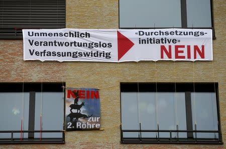 A banner demands to vote against an initiative of Swiss People's Party (SVP), demanding to deport criminal foreigners, is displayed over one demanding to vote against the construction of a second tube for the St. Gotthard road tunnel at an apartment building in Zurich, Switzerland February 15, 2016. The poster on top reads, "Inhuman - irresponsible - unconstitutional - enforcement initiative No". REUTERS/Arnd Wiegmann