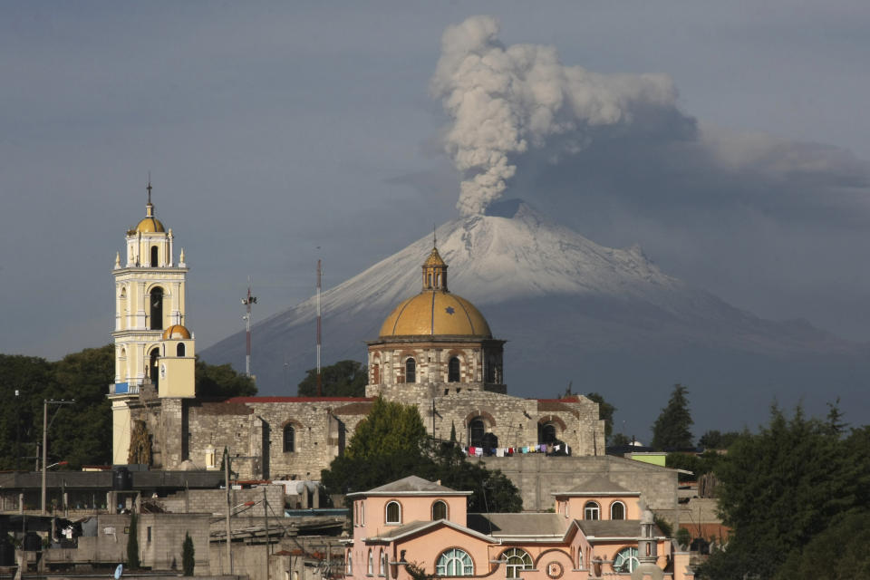 ARCHIVO - La iglesia principal de San Damián Texoloc, México, al frente del volcán Popocatépetl mientras expulsa cenizas y vapor a inicios de julio de 2013. La sabiduría sagrada de "El Popo" varía de pueblo a pueblo, pero la mayoría coincide en que el volcán no amenaza sus vidas. (AP Foto/J. Guadalupe Perez, Archivo)