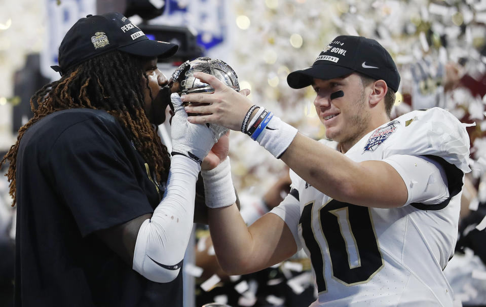 Central Florida linebacker Shaquem Griffin, left, kisses the championship trophy as Central Florida quarterback McKenzie Milton looks on after the Peach Bowl NCAA college football game against Auburn, Monday, Jan. 1, 2018, in Atlanta. Central Florida won 34-27. (AP Photo/John Bazemore)