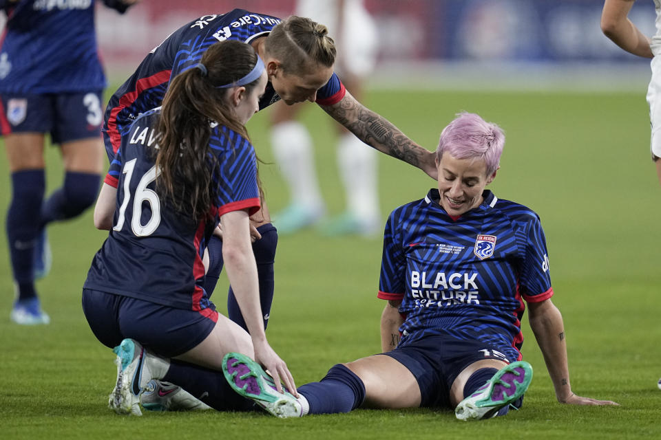 OL Reign forward Megan Rapinoe, right, stays down after an injury as teammates midfielder Rose Lavelle (16) and midfielder Jess Fishlock, center, check on her during the first half of the NWSL Championship soccer game against NJ/NY Gotham, Saturday, Nov. 11, 2023, in San Diego. (AP Photo/Gregory Bull)