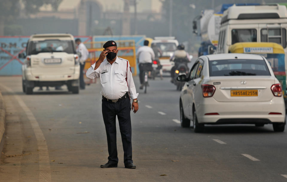 FILE- In this Nov. 4, 2019, file photo, a traffic officer wears a pollution mask and clears the irritants from his eyes in New Delhi, India. India is grappling with two public health emergencies: critically polluted air and the pandemic. Nowhere is this dual threat more pronounced than in the Indian capital New Delhi, where the spike in winter pollution levels has coincided with a surge of COVID-19 cases. (AP Photo/Manish Swarup, File)