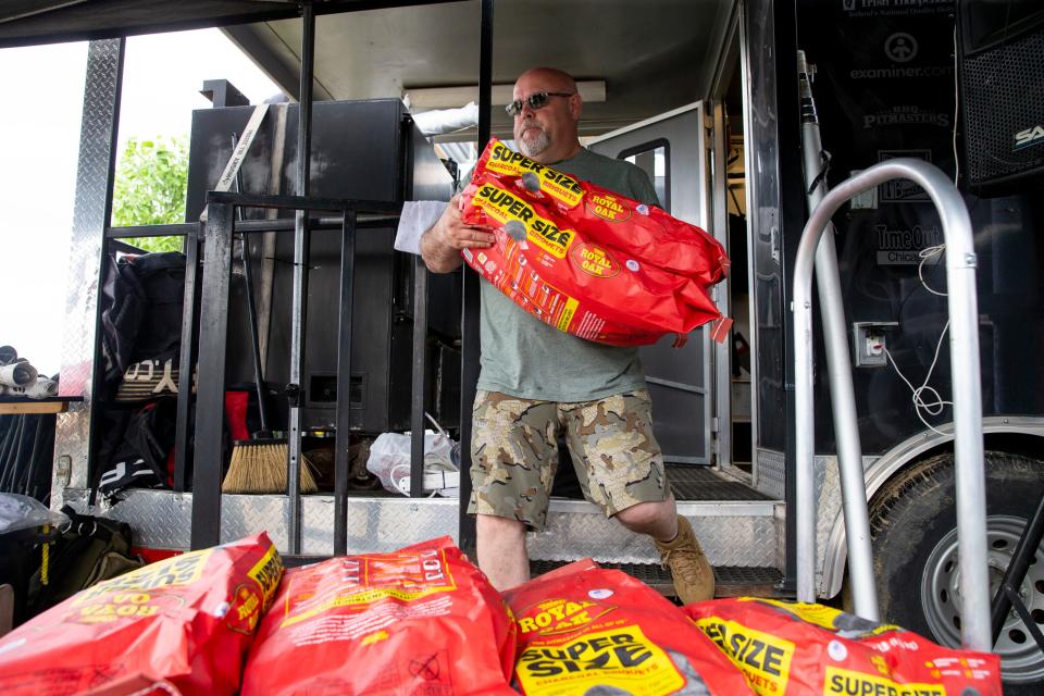 Dana Peterson, a team member with Peg Leg Porker, moves bags of charcoal briquets at their booth before the start of the Memphis in May World Championship Barbecue Cooking Contest at Tom Lee Park in Downtown Memphis on Wednesday, May 17, 2023.