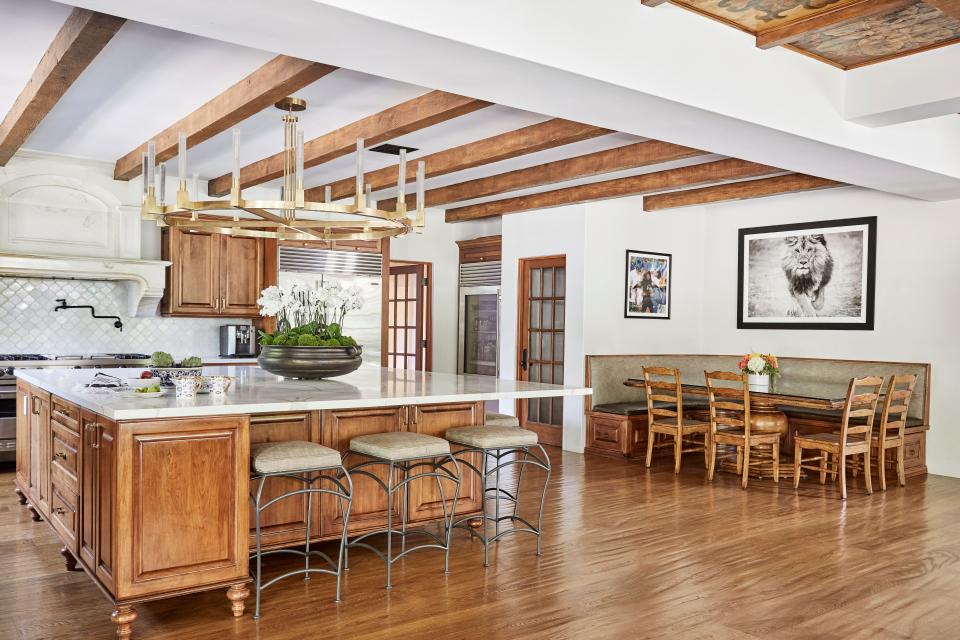 The kitchen area was expanded to accommodate a large family that loves to cook. Farahan used quartz in a Calacatta book-matched pattern for the countertops and custom-made the breakfast table chairs and bar stools. The pendant light is from RH Modern and the flowers are by Harumi Takata Design.