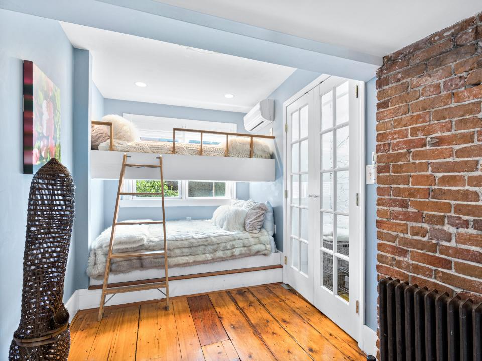 A room with exposed brick on the left and bunkbeds in the middle