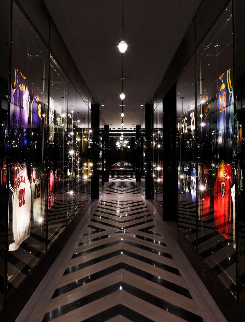 Uniforms of basketball legends line the jersey hall. Gabriel Scott lighting.