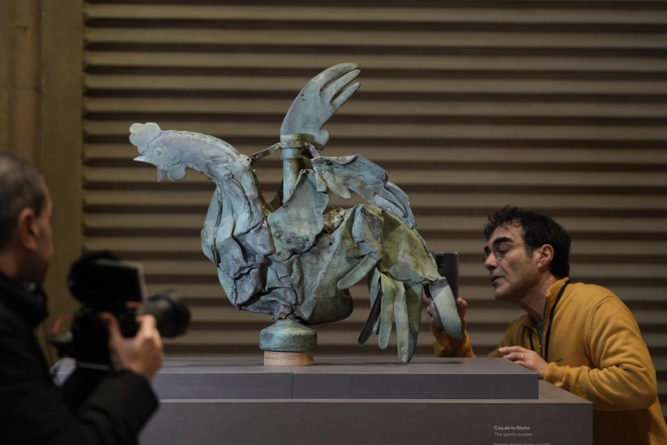 People take pictures of the rooster which sat atop of the spire of the Notre-Dame cathedral, at the Cité de l'architecture et du patrimoine in Paris, Friday, Dec. 15, 2023. Roosters are a symbol of France. The small bird that adorned Notre Dame plunged to the ground in the April 2019 fire that collapsed the spire and consumed the roof. (AP Photo/Thibault Camus)