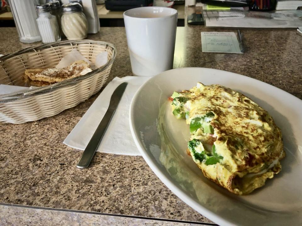 A veggie omelet with a basket of wheat toast and a cup of freshly brewed coffee.
