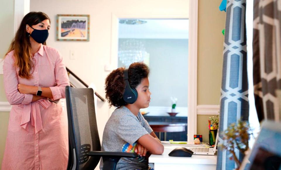 As his mother Juliette takes a peak, Harper Grimmett attends his day of classes as a sixth grader at Ligon Middle School while at their home in Raleigh, N.C. Monday, August 17, 2020. They enrolled in the Wake County Virtual Academy in the 2020-21 school year.