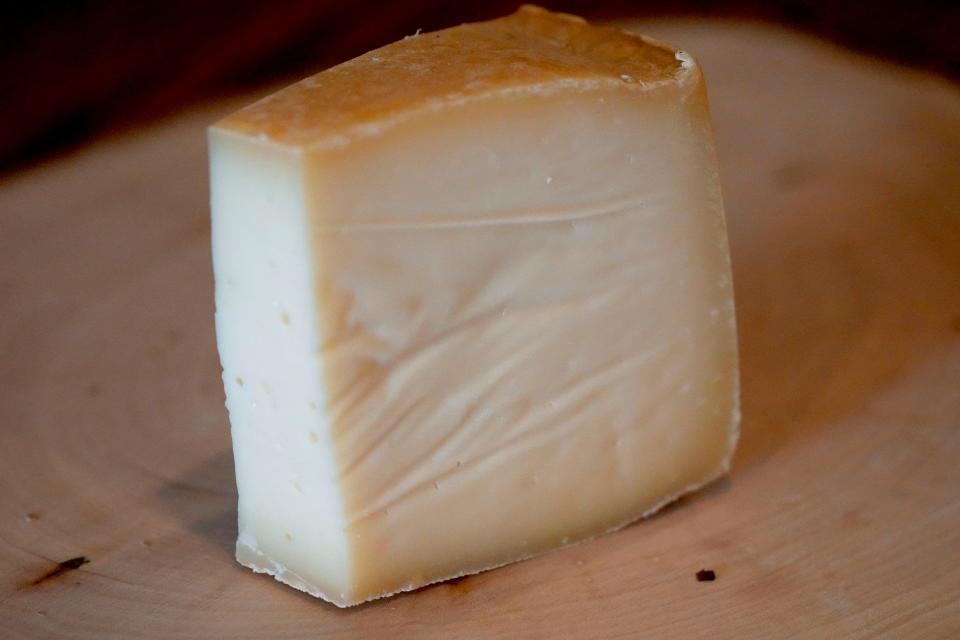 A slice from a wheel of Mount Raclette, aged raclette by Alpinage Artisan Cheese. Because the cheese is aged naturally, the rind is edible.