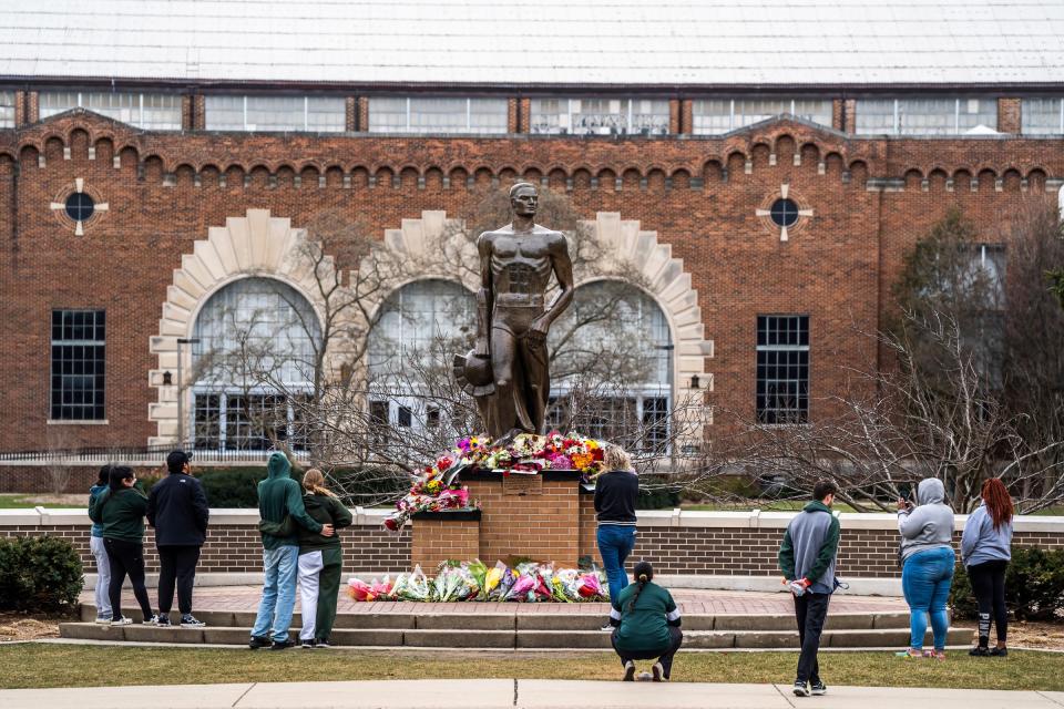 People leave flowers at the base of the Sparty statue following an active shooting incident on the Michigan State University campus in East Lansing on Tuesday, February 14, 2023, that left three people dead and multiple injured.