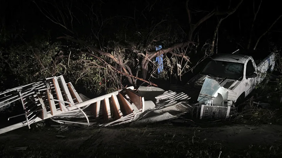 A mangled spiral staircase in the brush next to a white pickup truck near the Sanibel Causeway.