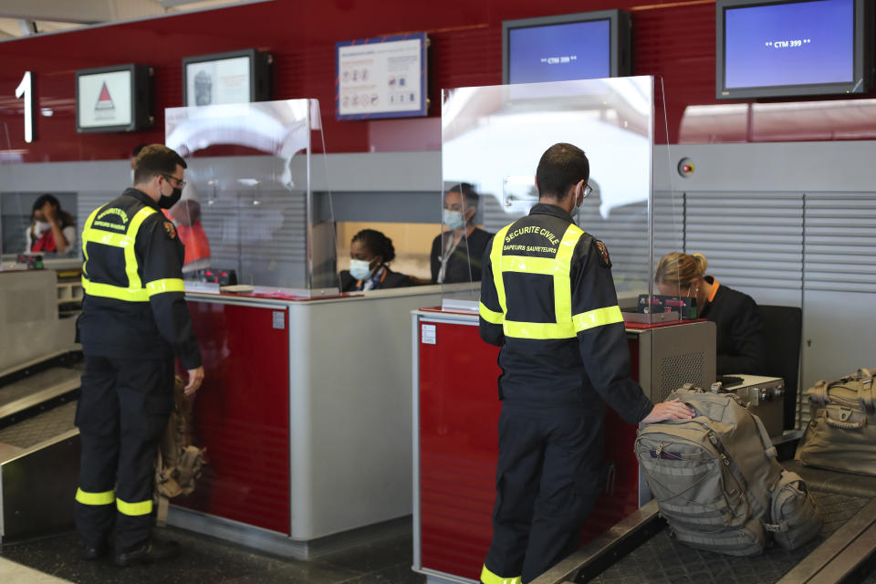 Members of the Securite Civile rescue organisation wait at the boarding desk at Charles de Gaulle airport, north of Paris, Wednesday, Aug.5, 2020. France is sending two planes to Lebanon on Wednesday with dozens of emergency workers, a mobile medical unit and 15 tons of aid. The aid is expected to arrive Wednesday afternoon and should allow for the treatment of some 500 blast victims, according to French President Emmanuel Macron's office. (AP Photo/Thibault Camus)