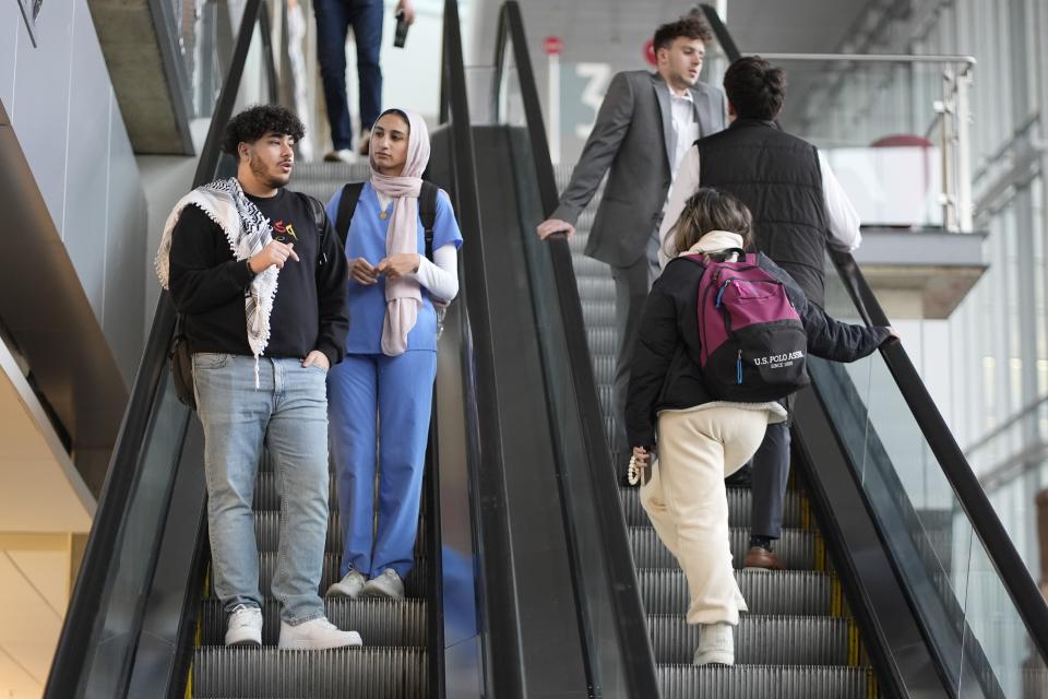 Yaqoub Saadeh and Tasneem Nada speak as they ride the escalator to the bottom floor at IUPUI, Wednesday, Feb. 7, 2024, in Indianapolis. The heart of most opposition leveled against the bill from pro-Palestinian and anti-Israel voices. State senators passed the amended version of the bill Tuesday in a 42-6 vote. But it needs final approval from the House, where the bill originated, before becoming law. (AP Photo/Darron Cummings)