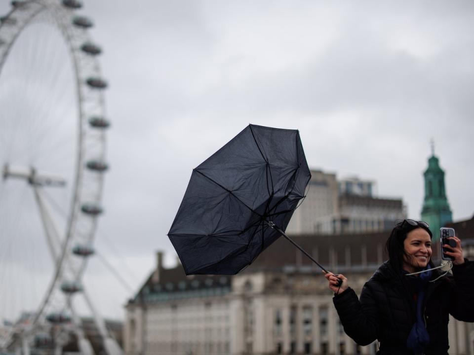 People walk across Westminster Bridge against strong winds in the rain with the London Eye in the background (EPA)