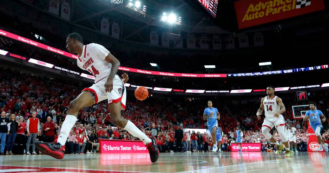 N.C. State’s Ernest Ross (24) saves the ball from going out of bounds, passing it to Casey Morsell (14) for a basket during N.C. State’s 77-69 victory over UNC at PNC Arena in Raleigh, N.C., Sunday, Feb. 19, 2023.