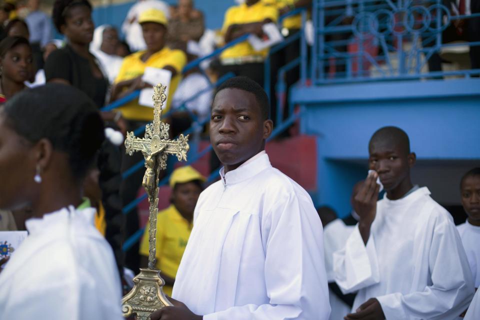 An altar boy carries a cross during a Mass lead by Cardinal Chibly Langlois in Port-au-Prince, Haiti, Sunday, March 9, 2014. Cardinal Chibly Langlois reminded Sunday's crowd at the soccer stadium that many would go hungry or wouldn't be able to survive were it not for the kindness of others. (AP Photo/Dieu Nalio Chery)