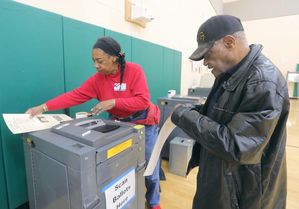 Poll worker Laneita Jones helps process a ballot for William Travis on Tuesday at Helen Arnold Community Learning Center in Akron.