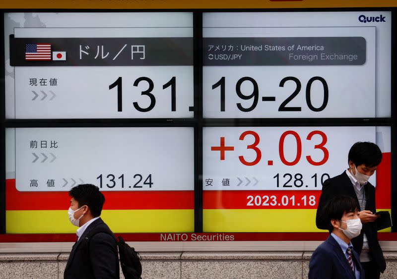 Passersby walk past electric monitors displaying the exchange rates in Tokyo