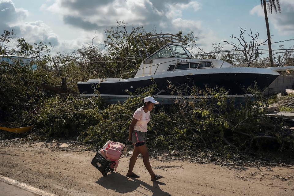 A resident walks past a boat as she arrives to her home to salvage personal items and food in the aftermath of Hurricane Otis in Acapulco, Mexico, Friday, Oct. 27, 2023.