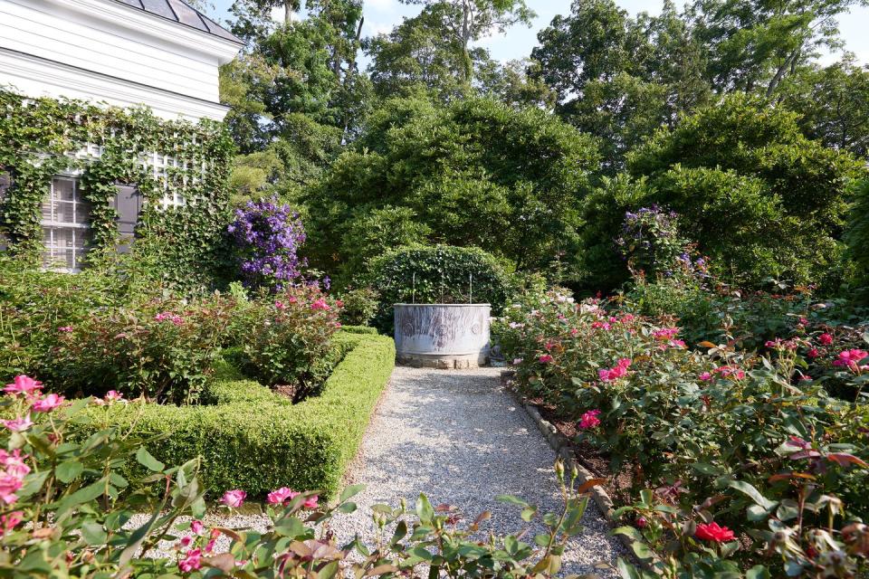 a path through a garden with bridge of flowers in the background